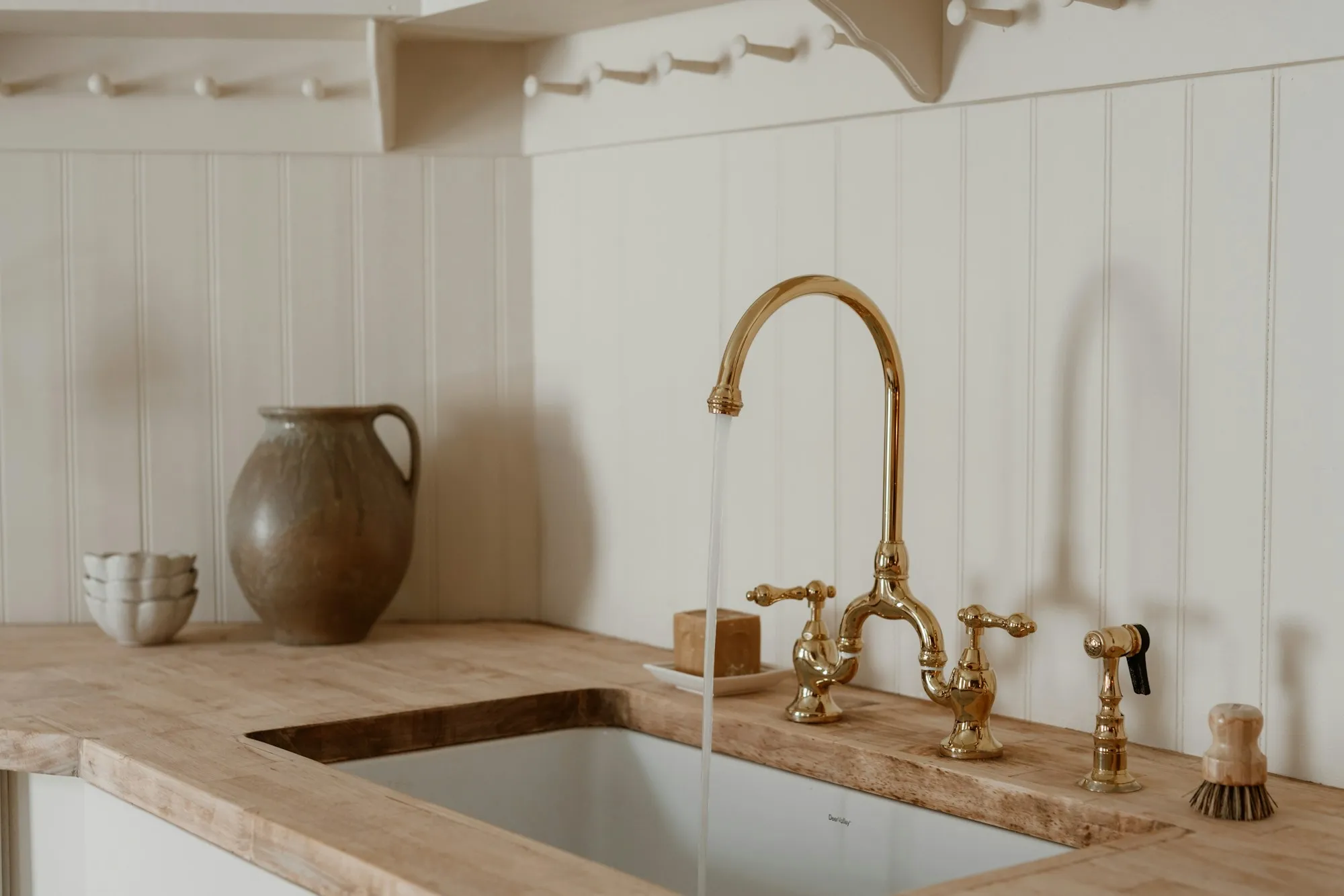 Brass bridge faucet over a stone kitchen sink
